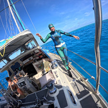 Load image into Gallery viewer, diver Aimrite blue/green stinger suit walking down the side of sailboat