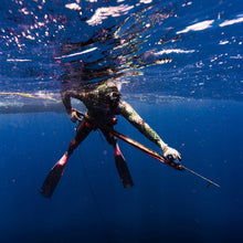Load image into Gallery viewer, Diver underwater with a Vendetta speargun, surrounded by blue water and light reflections.