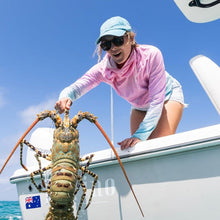 Load image into Gallery viewer, Person on a boat releasing a large lobster into the ocean with another person assisting.