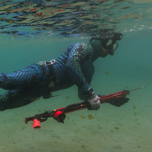 Load image into Gallery viewer, Person snorkeling underwater wearing a wetsuit, mask & holding Vengeance roller speargun