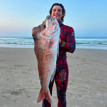 Load image into Gallery viewer, Diver holding large snapper on sandy beach
