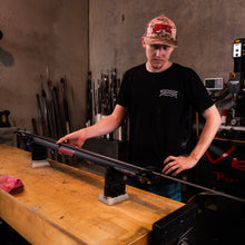 Load image into Gallery viewer, Person looking at aimrite vendetta roller speargun while it sits on a benach with workshop in background
