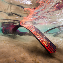 Load image into Gallery viewer, diver swiming in shallow sandy water wearing aimrite freeiving fins (hex inferno)

