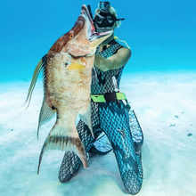 Load image into Gallery viewer, person in aimrite stinger suit sitting on the sandy bottom in clear water
