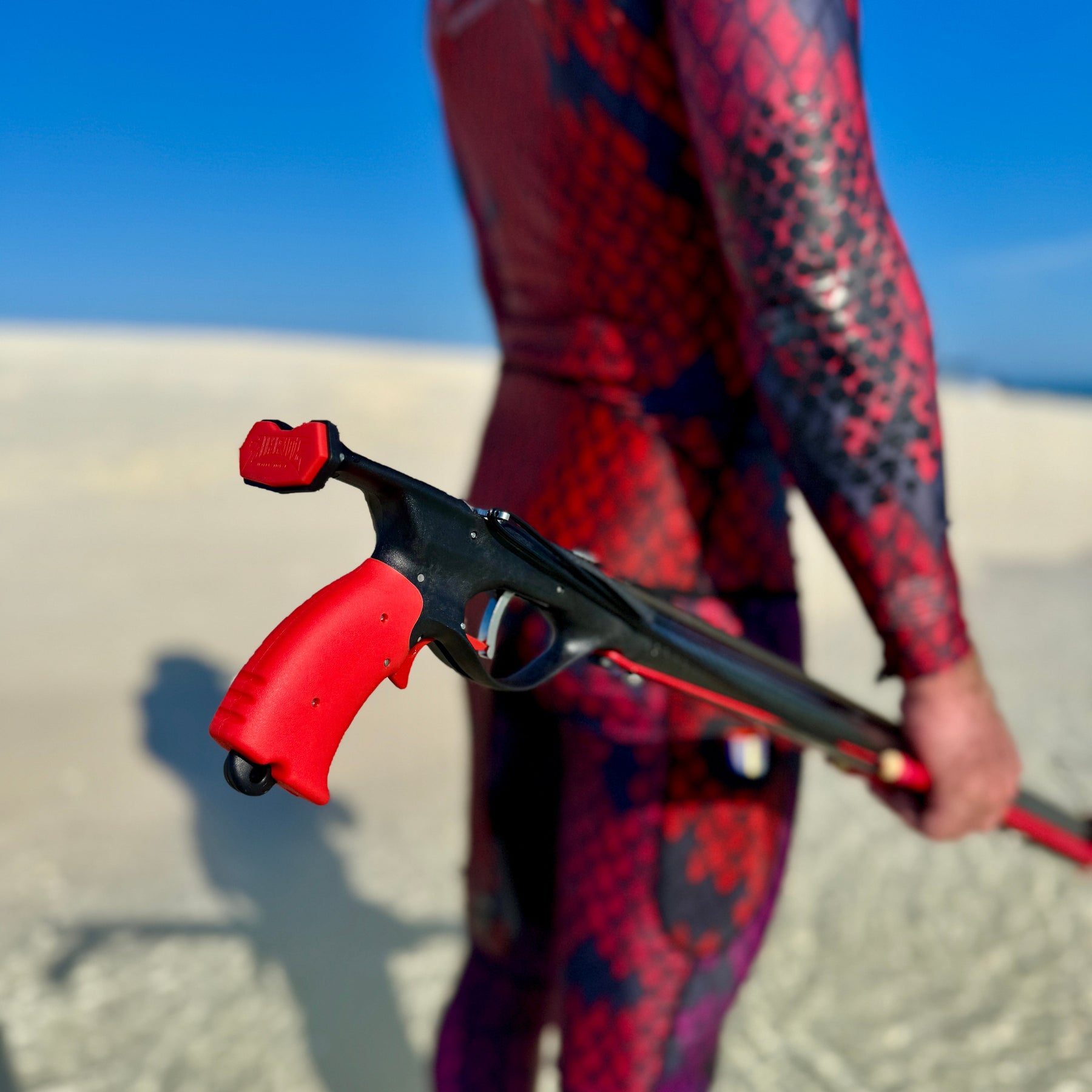Spearo on a sandbar carrying an Aimrite ENVY carbon roller speargun